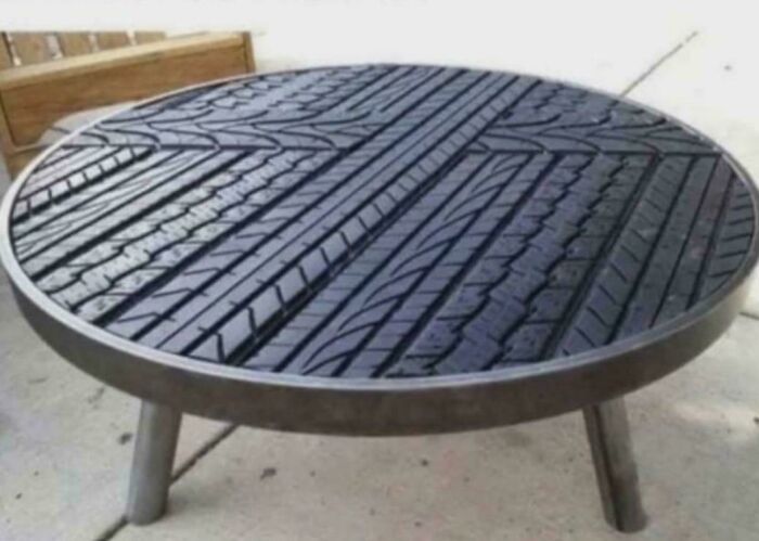 Round outdoor table with tire tread surface and metal legs, showcasing redneck engineering creative MacGyvering.