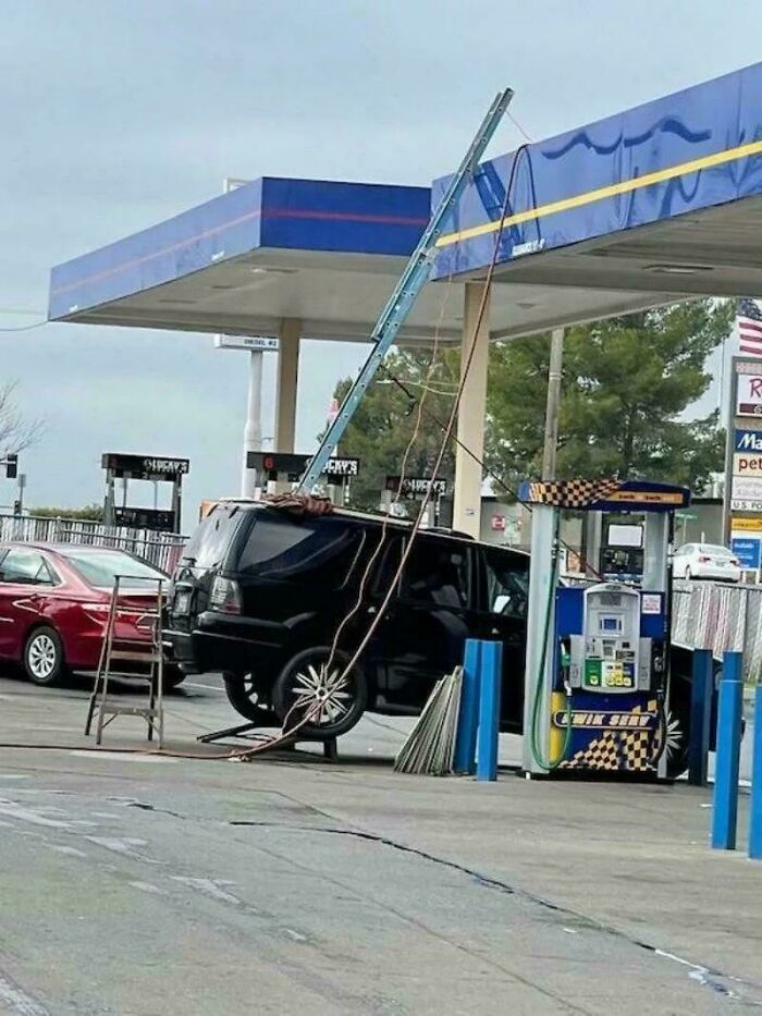 Black SUV lifted with ladder and ropes at gas station demonstrating redneck engineering creative MacGyvering.