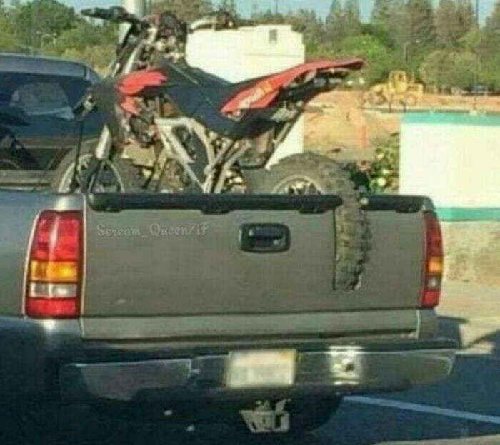 Pickup truck with a dirt bike secured in the bed in a clever example of redneck engineering and creative MacGyvering.