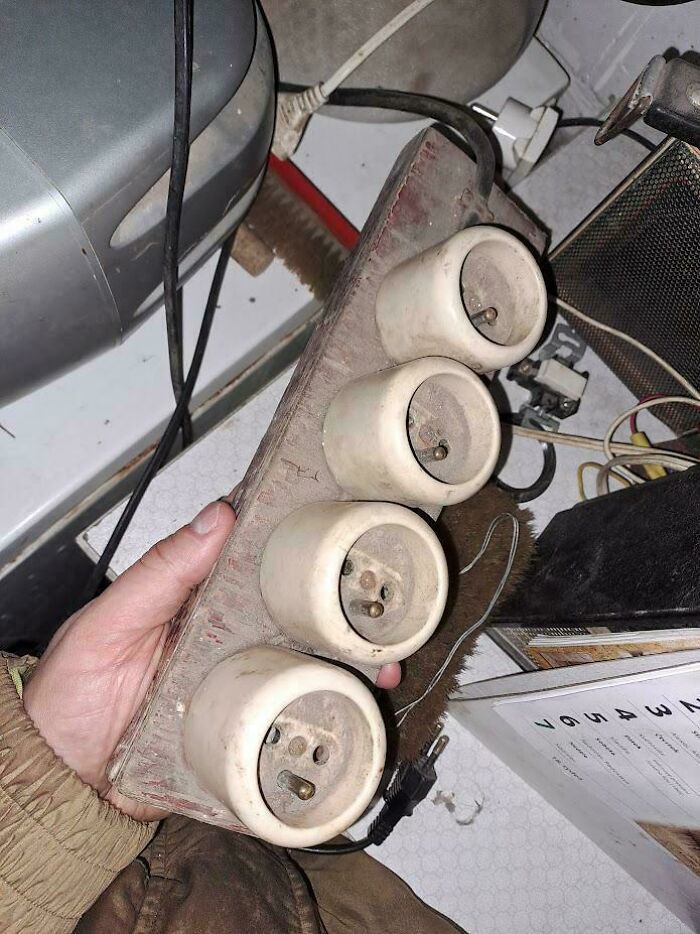 Hand holding a vintage homemade electrical outlet panel showcasing creative redneck engineering and MacGyvering skills.