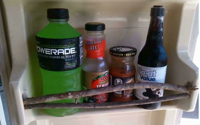 Fridge door secured with sticks as a creative redneck engineering solution to hold bottles in place.