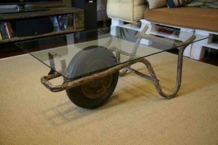 Creative redneck engineering repurposes a wheelbarrow frame with a glass top into a unique and functional coffee table.