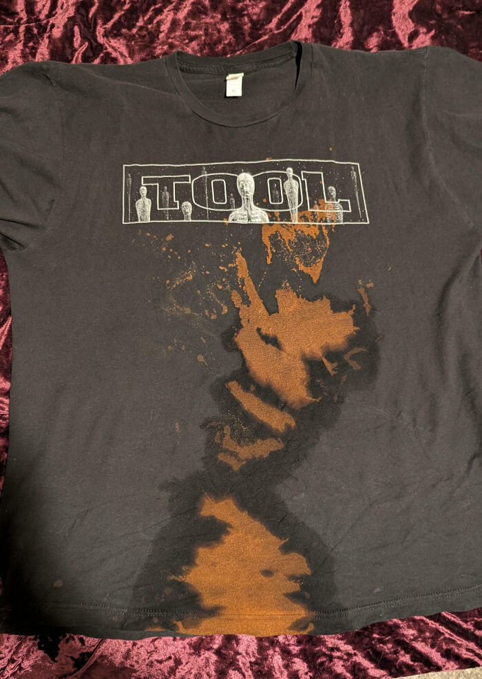 Black Tool band shirt with large bleach stains resembling a work fail accident on fabric.