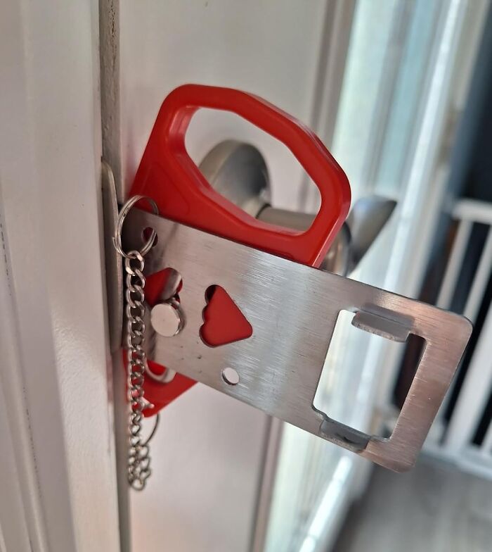 Portable door lock travel essential with red handle and metal latch installed for added security during trips.
