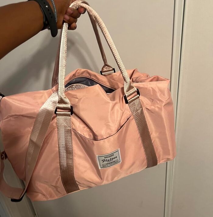 Hand holding a pink travel bag with beige straps, a key item among travel essentials for hot girl summer trips.
