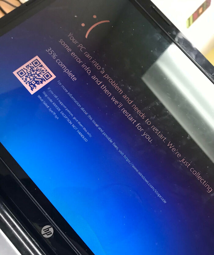 Laptop screen showing a blue error message and QR code during a work fail causing the system to restart unexpectedly.