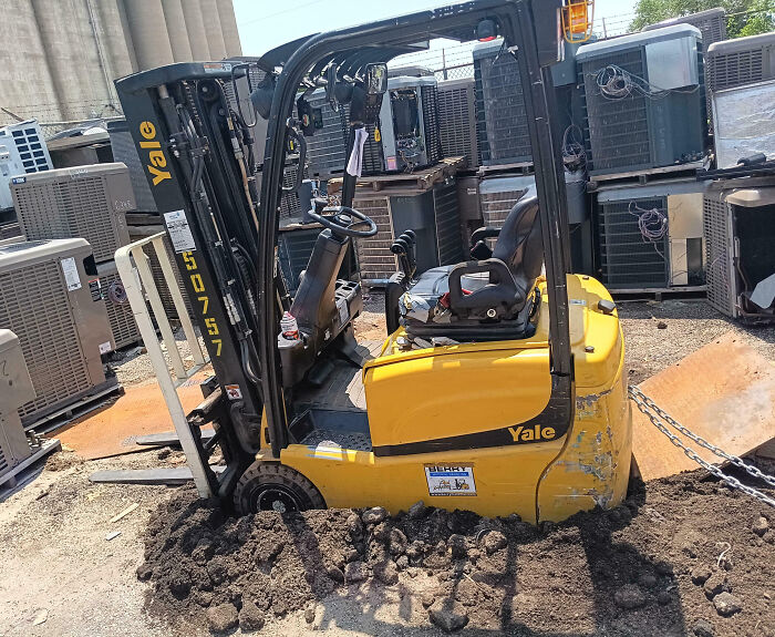 Yellow forklift stuck in mud at a worksite, showcasing one of the epic work fails in an industrial setting.