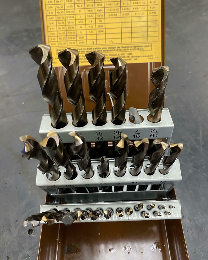 Set of drill bits with several broken pieces displayed on a workshop surface, highlighting epic work fails.