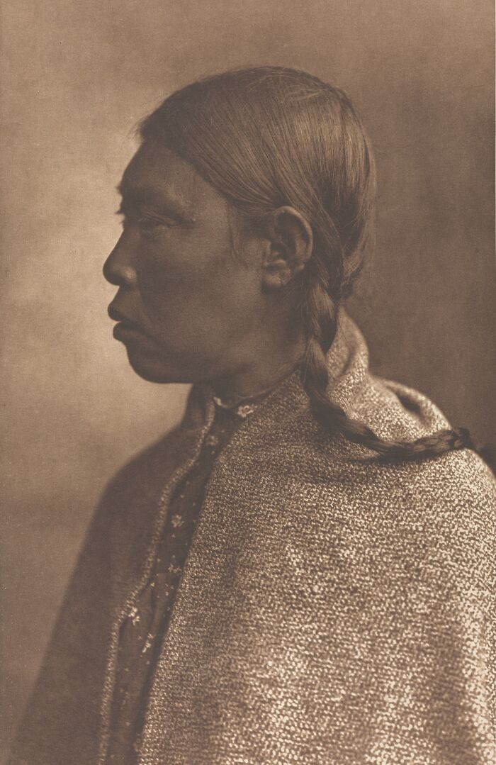 Profile of Native American man with braided hair wrapped in woven fabric in a powerful Edward S. Curtis photo preserving history