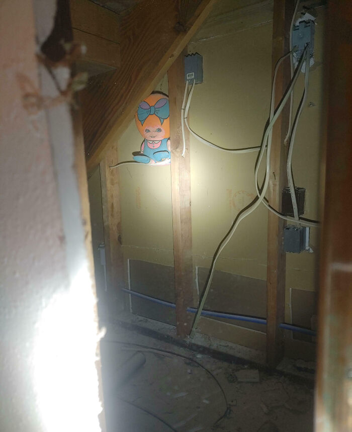 Work fails showing unfinished wall with exposed wires and a painted cartoon girl hidden behind wooden beams.