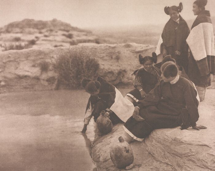 Native American women and children by water’s edge in a vintage Edward S. Curtis photo preserving Native American history.