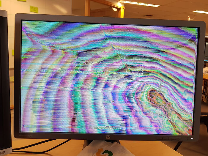 Computer monitor showing colorful distorted and c*****d screen, an epic work fail in an office setting.