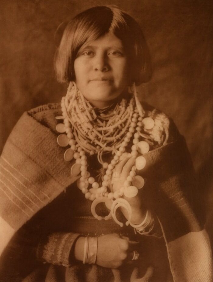Native American woman wearing traditional jewelry and clothing in a powerful Edward S. Curtis photo preserving history.
