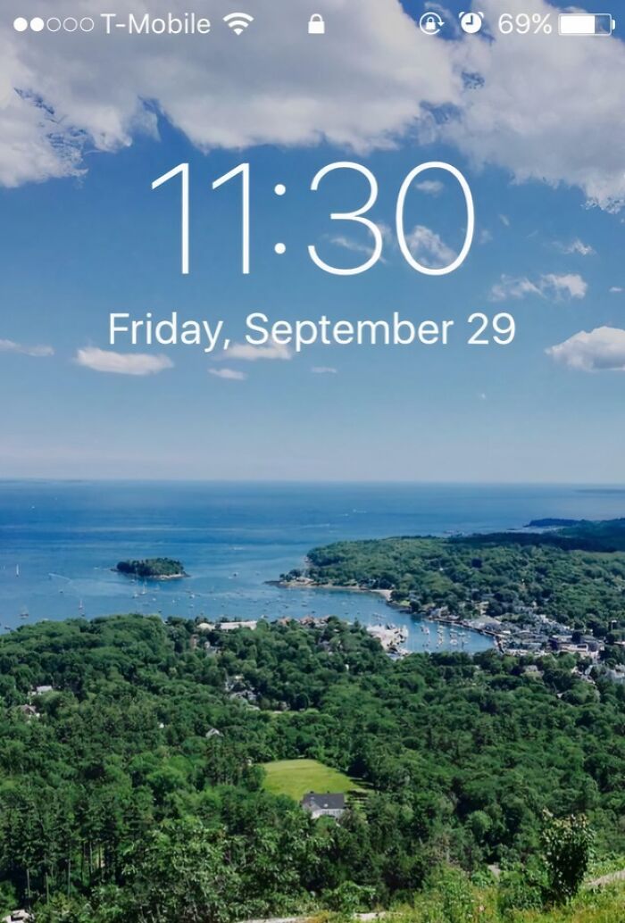 Scenic coastal view with green trees and blue ocean under a partly cloudy sky on a clear day.