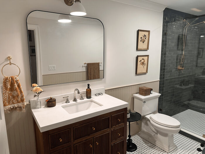 Modern bathroom living space revamp with dark wood vanity, white countertop, glass shower, and decorative wall art.
