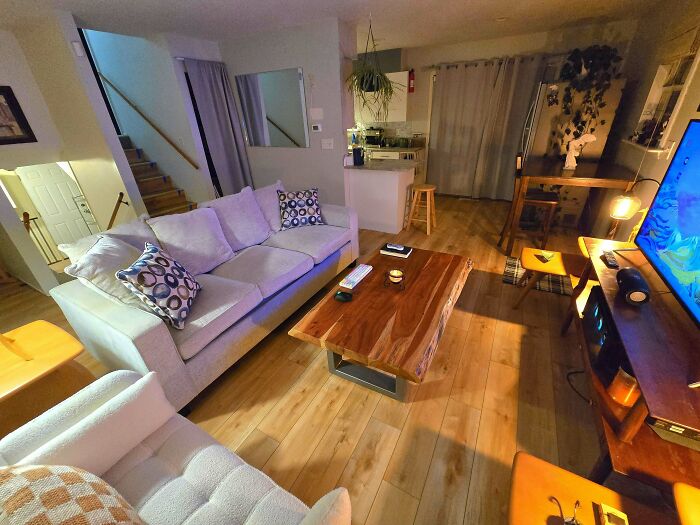 Cozy living space revamped with modern furniture, wooden flooring, and warm lighting, showcasing a stylish home interior.