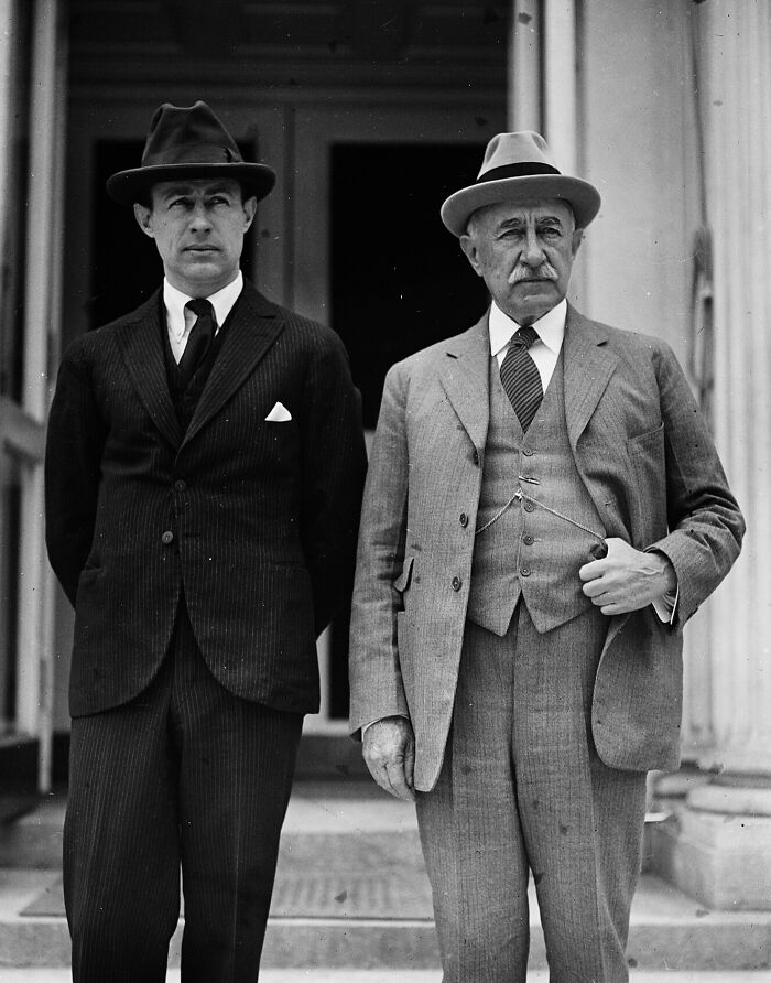 Two men in suits and hats standing outside a historic building, vintage Washington D.C. photo from the 1920s.