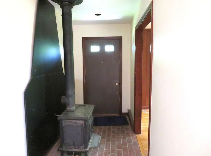 Narrow hallway with a wood stove blocking the entrance, an example of failed creativity in home design.