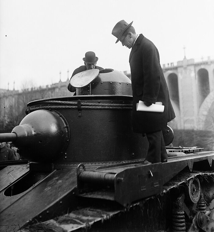 Two men in 1920s attire inspecting a tank in Washington, D.C., showcasing vintage US military history.
