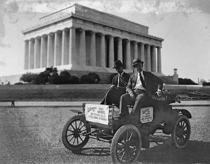 Two men in vintage 1901 Oldsmobile car in front of the Lincoln Memorial, historical photo of Washington D.C.