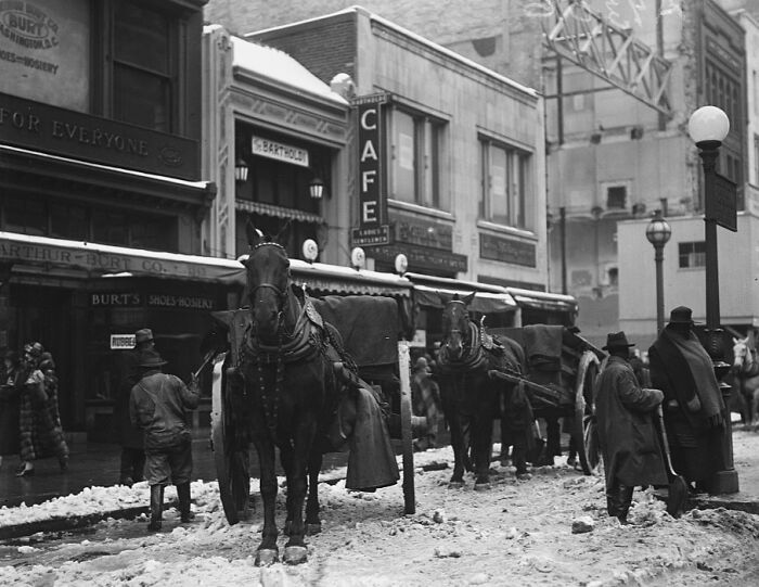 Horses pulling carriages on a snowy street in vintage Washington D.C. during the 1920s historical era.