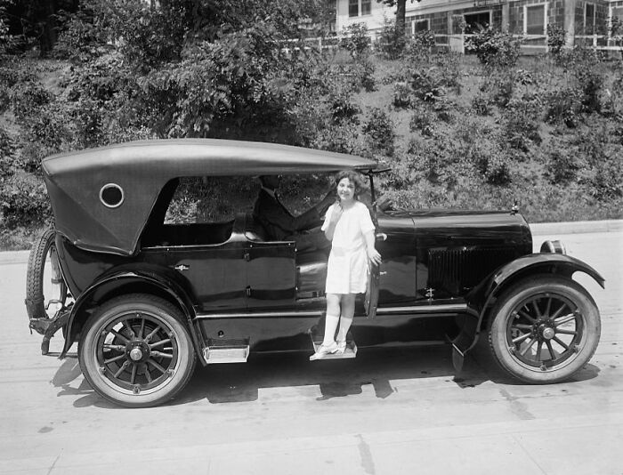 Vintage 1920s Washington D.C. scene showing a woman stepping out of a classic car on a sunny street.