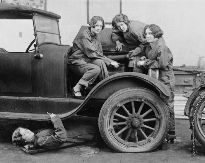 Four women in mechanic overalls working on a vintage car, a historical photo of Washington, D.C., from the 1920s.