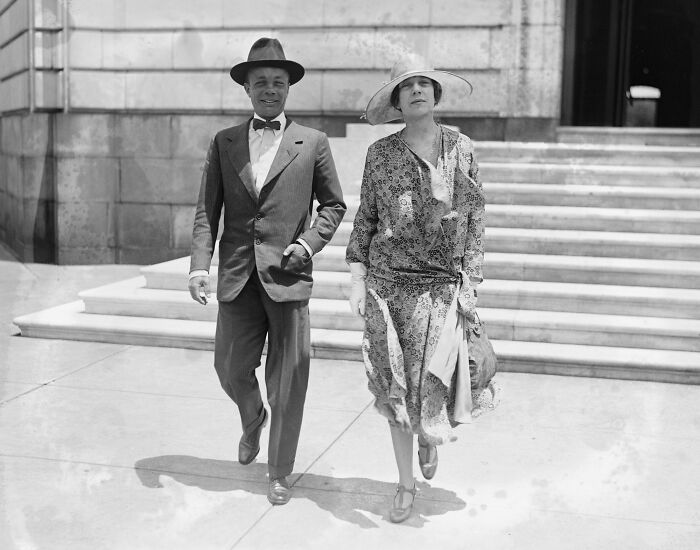 Man and woman dressed in 1920s fashion walking outside a building in historical photos of Washington DC vintage US.