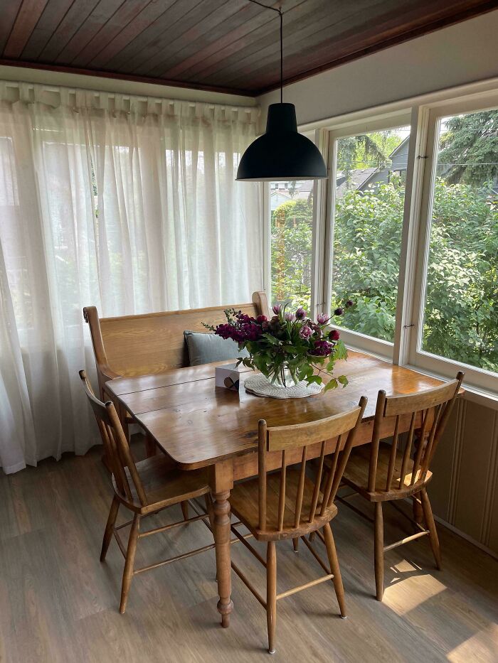 Cozy living space revamp with wooden dining table, chairs, bench seating, and natural light from large windows.