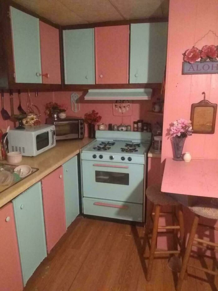 Retro kitchen revamped with pastel pink and blue cabinets, vintage stove, and cozy dining area, showcasing living space makeover.