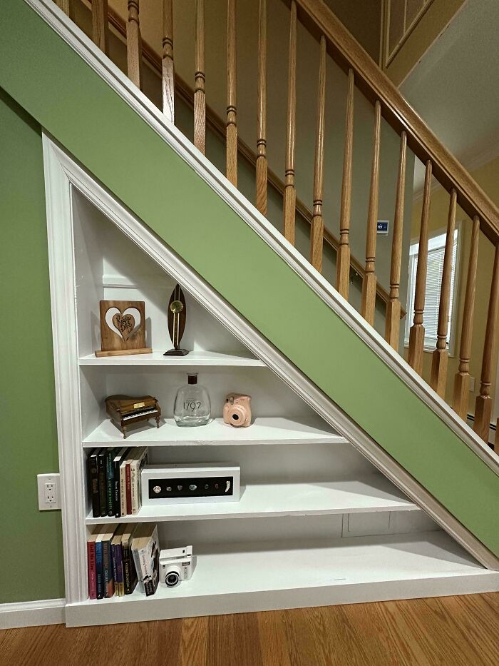 Built-in white shelving under staircase with decorative items and books, showcasing creative living space revamp ideas.