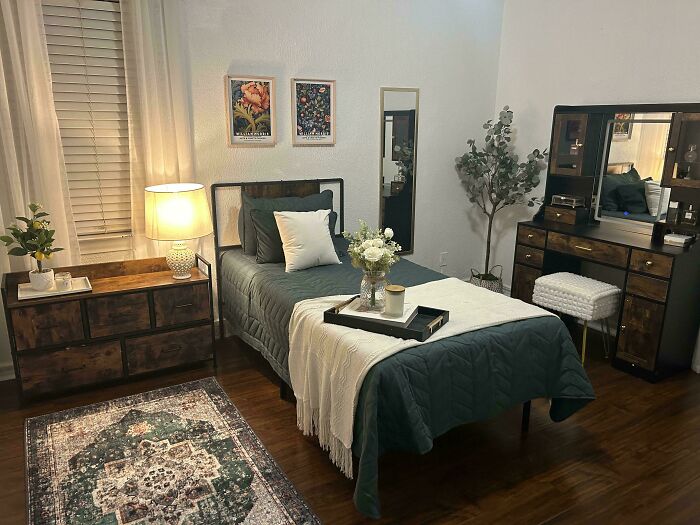 Cozy living space revamped with modern furniture, soft lighting, decorative plants, and stylish bedding in a warm bedroom setting.