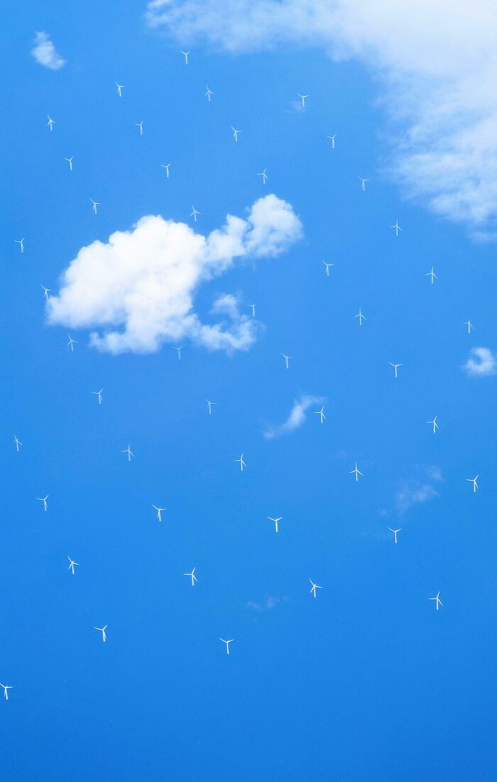 Wind turbines scattered across a blue sky with a single white cloud, capturing something mildly interesting to share.