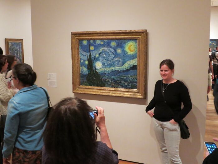 Visitors admiring and photographing a famous Starry Night painting, showcasing top locations of the most famous paintings.