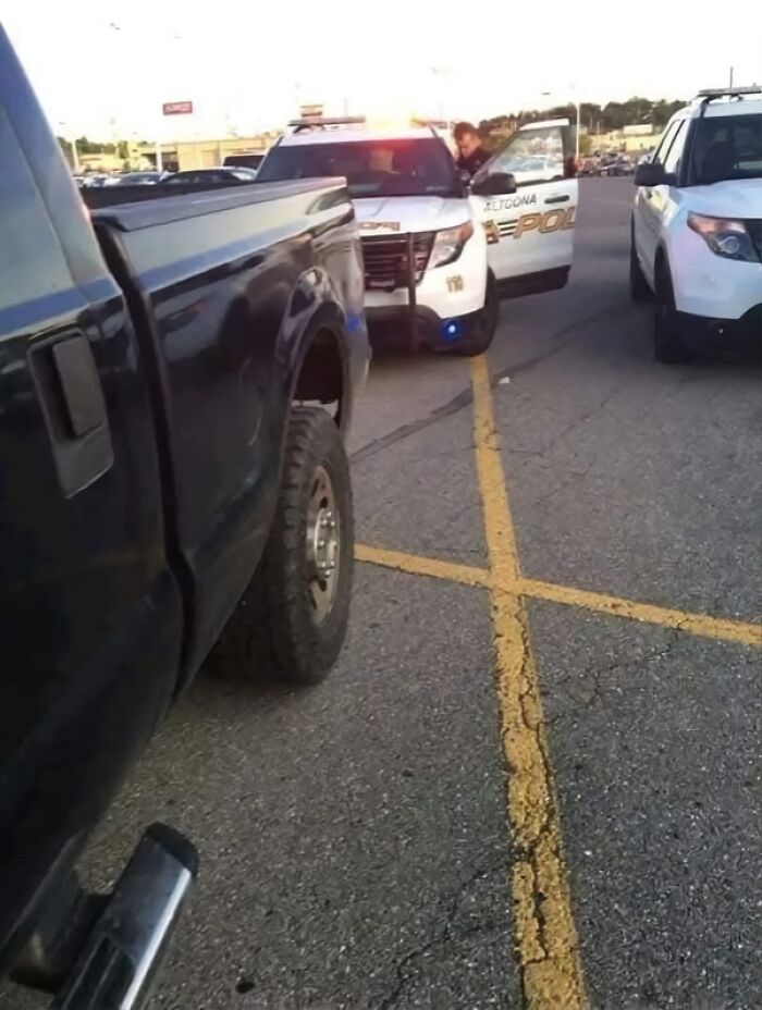 Police SUV with lights on parked behind a black pickup truck in a parking lot at sunset, peaceful scene.