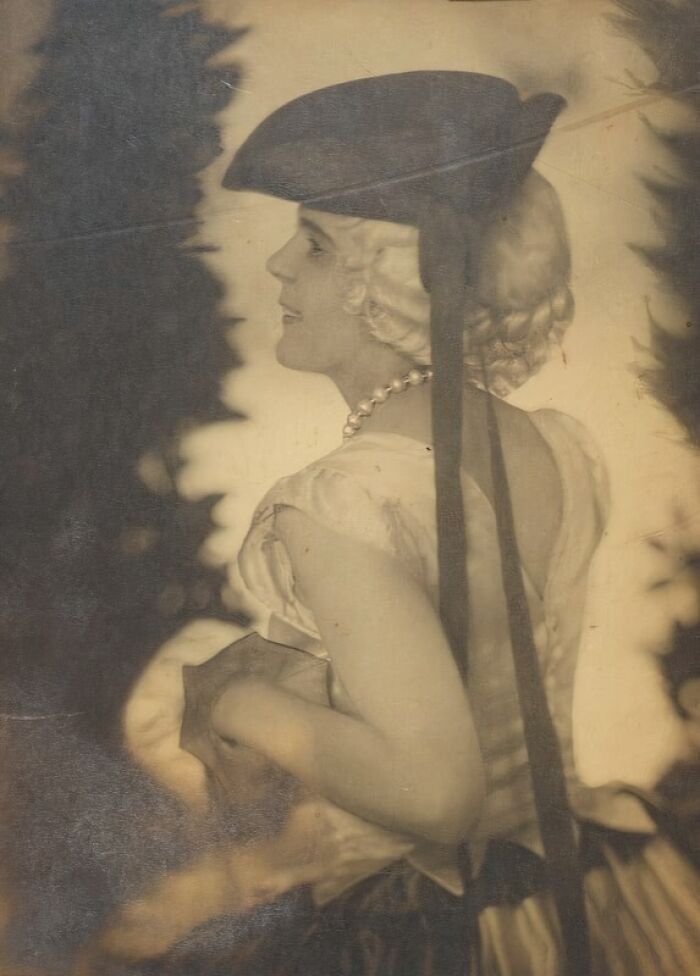 Vintage sepia photo of a woman from the 1900s wearing a hat and pearl necklace, showcasing the beauty of women in that era.