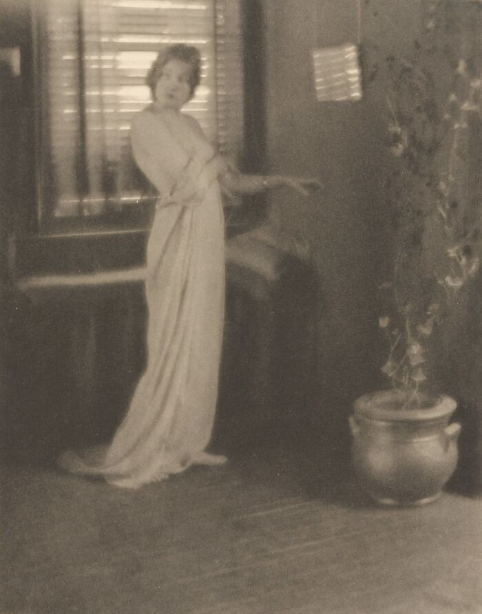 Vintage photo of a woman in a flowing dress captured indoors highlighting the beauty of women from the 1900s era.