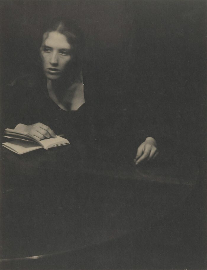 Black and white old photo of a woman reading a book, capturing the beauty of women from the 1900s.