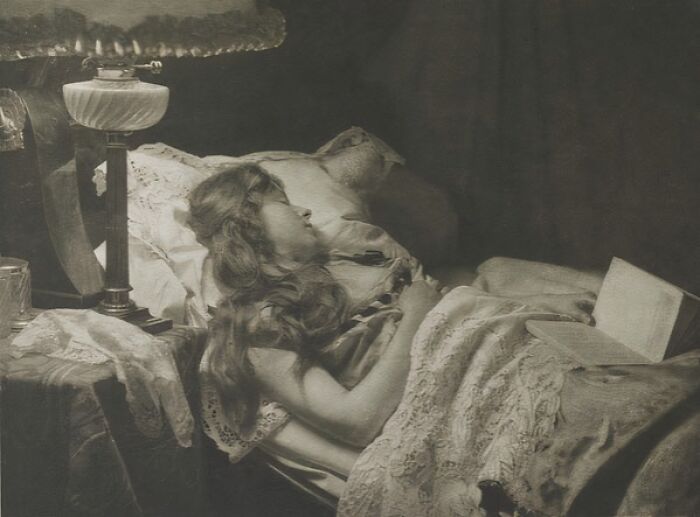 Vintage photo of a woman from the 1900s resting in bed, showcasing the timeless beauty of women from the early 20th century.