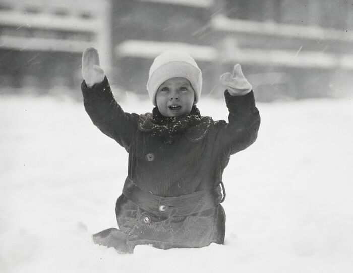 Child dressed in winter clothes playing in the snow in vintage historical photos of Washington D.C. from the 1920s.