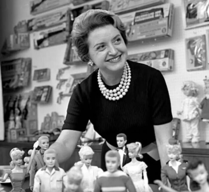 Woman smiling behind a collection of vintage dolls in a unique old photo with an incredible story behind it.