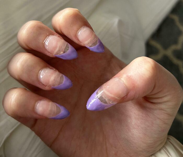 Close-up of broken purple French tip nails showing a salon glow-up gone wrong with damaged nail polish.