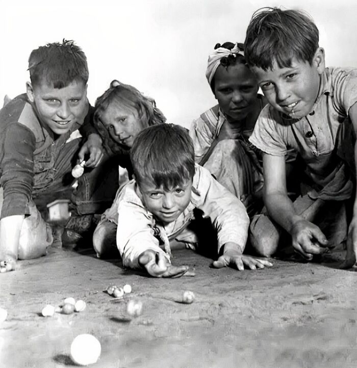 Group of kids playing marbles in a unique old photo showing joyful childhood moments and vintage outdoor fun.