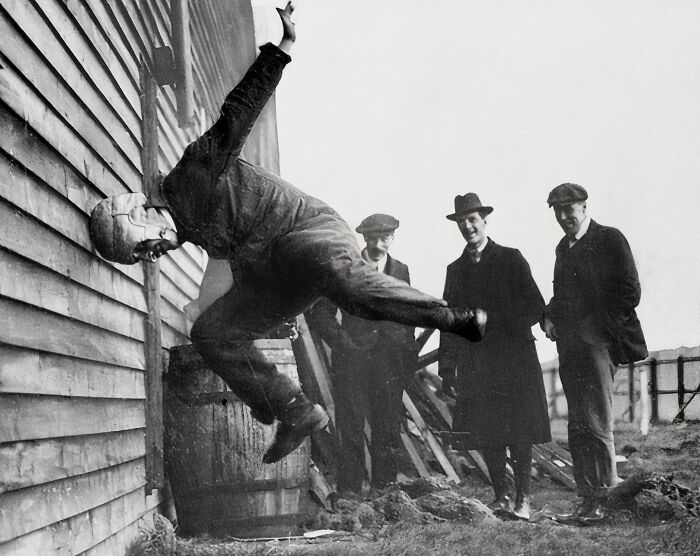 Vintage photo showing a man in mid-air crash into a building while three men in old attire watch nearby unique old photos.