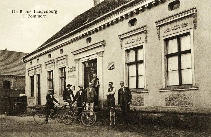 Black and white historical photograph of men with bicycles outside a building depicting the world 100 years ago.
