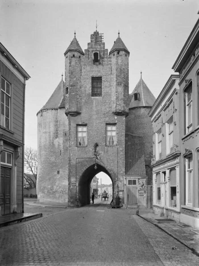 Historical photograph of a medieval gate in a cobblestone street showing what the world looked like 100 years ago.