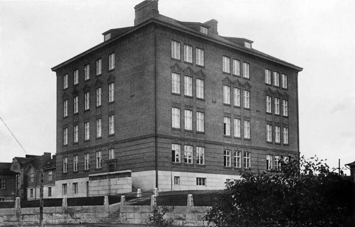Historic black and white photograph of a large brick building showcasing architecture from 100 years ago.