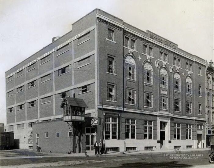 Historic photograph of a 100-year-old Behrens D**g Co. building with people standing outside on a city street.