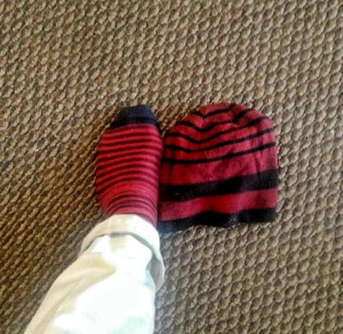 Red and black striped sock matching a beanie on a textured carpet showing a real-life glitch in the Matrix.