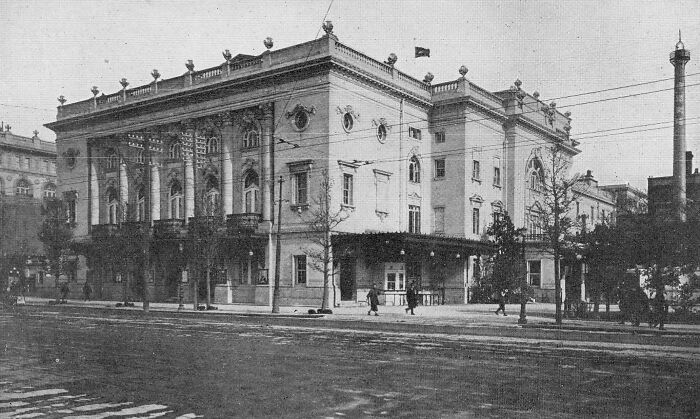 Historic black and white photo showing a grand building and street scene from historical photographs 100 years ago.